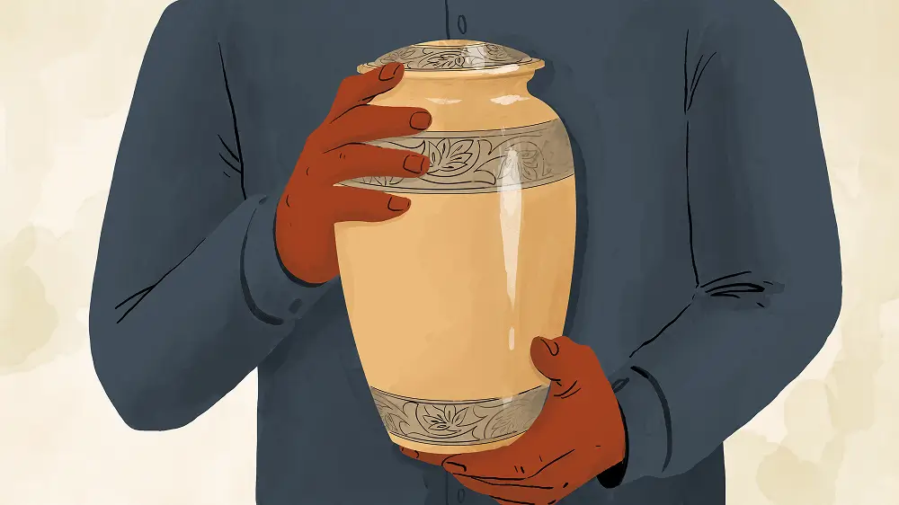 A person in a dark shirt holds a decorated beige urn with both hands.